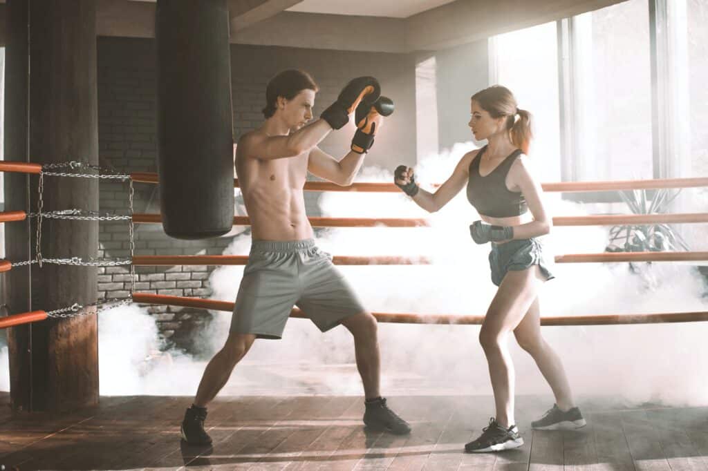 Boxing workout. Couple man and woman boxing together in the boxing ring at the gym. Sport box