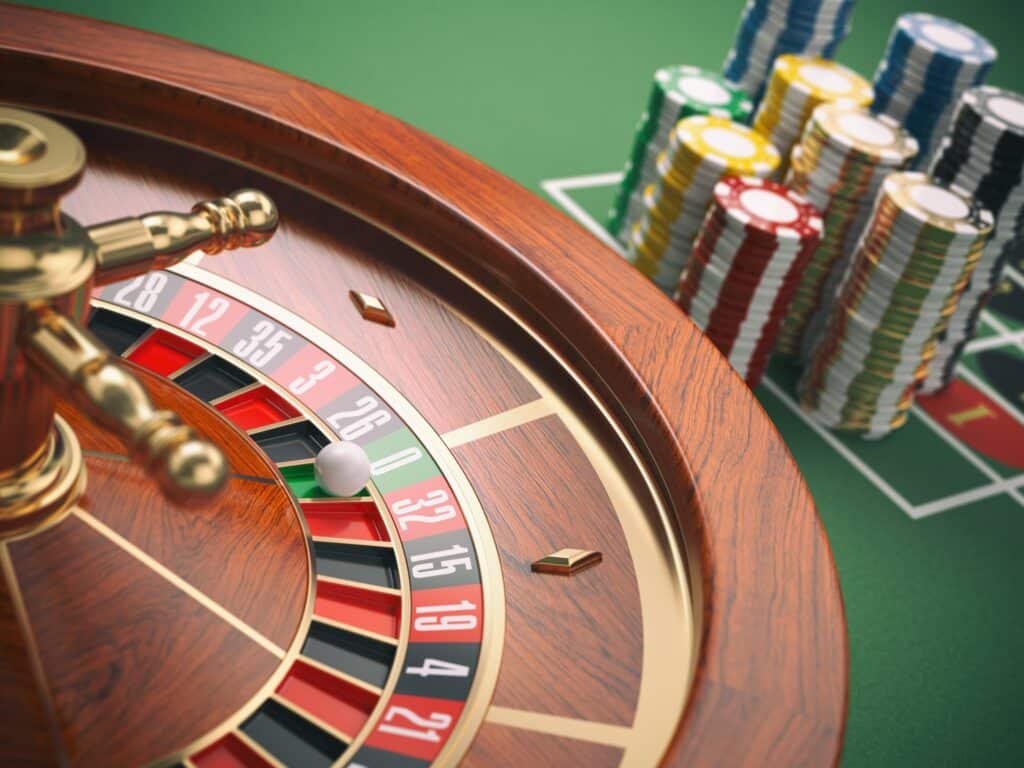 Casino roulette wheel with casino chips on green table. Gambling