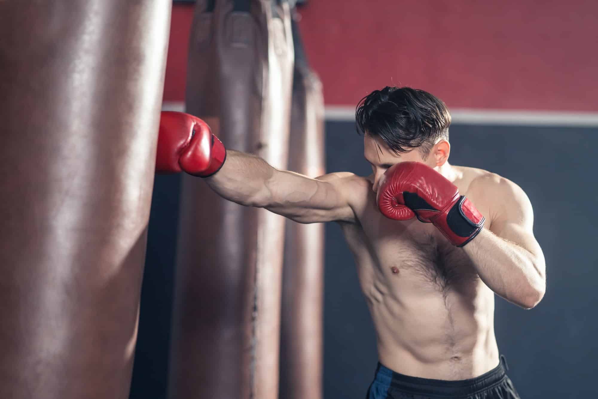 Caucasian bodybuilder man shirtless athlete wear boxing gloves, doing boxing workout exercise