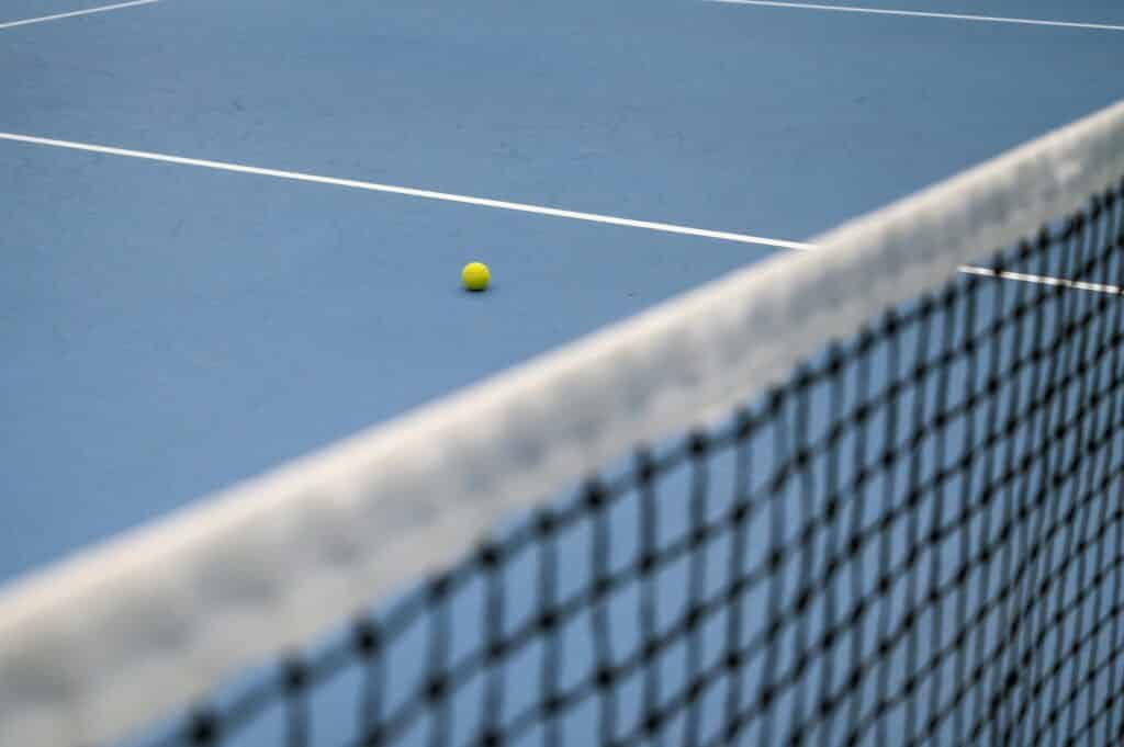Tennis ball on blue hard tennis court. Tennis net.