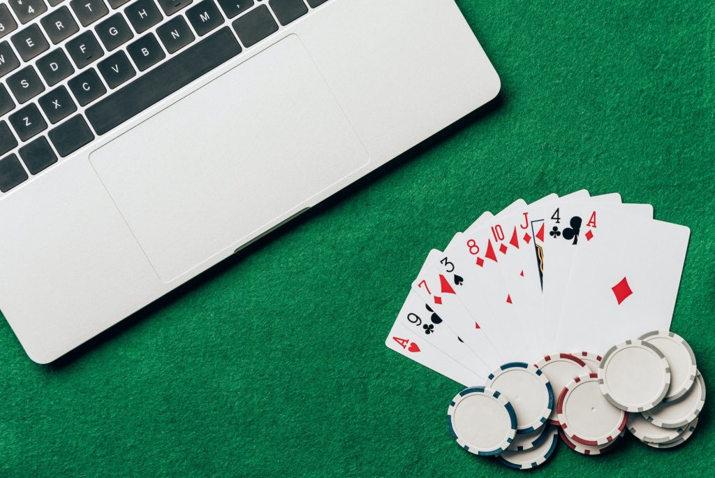 Playing cards and chips on casino table by laptop