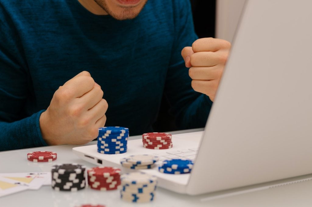 Unrecognizable gamer man playing with his laptop from home to casino games