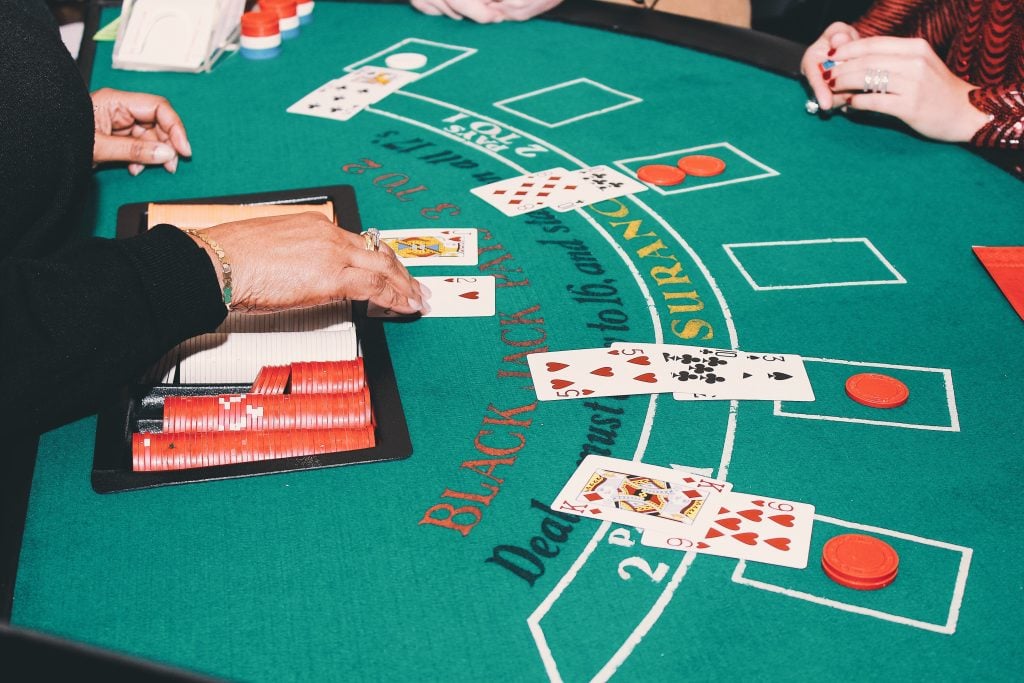 A blackjack dealer shows her cards to a table of hopeful bettors.