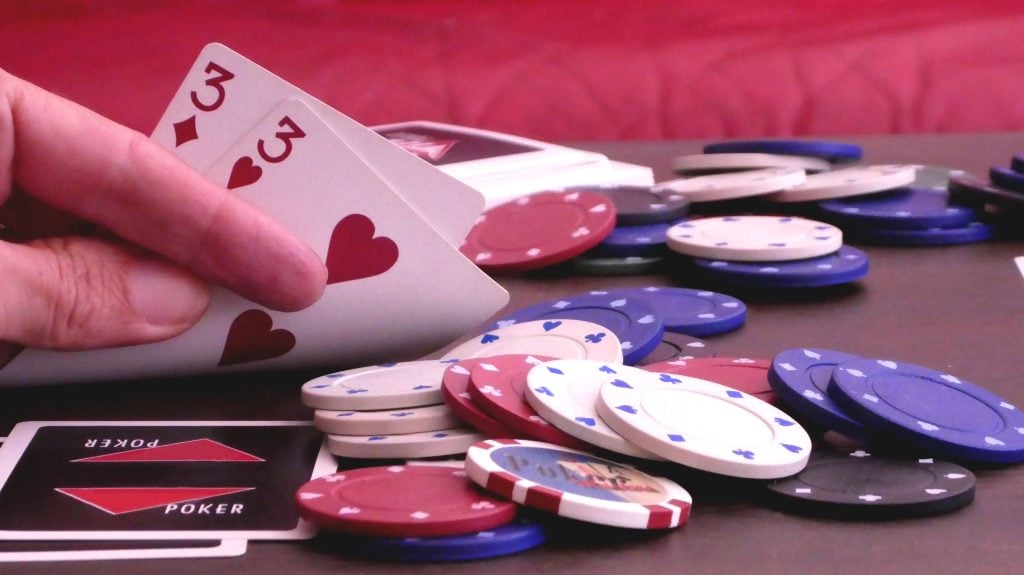Hand holding cards on table with poker chips