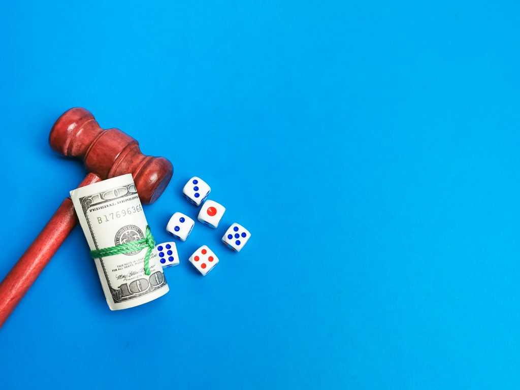 Image of dices,fake money and gavel against blue background. Law and regulation of gambling concept.