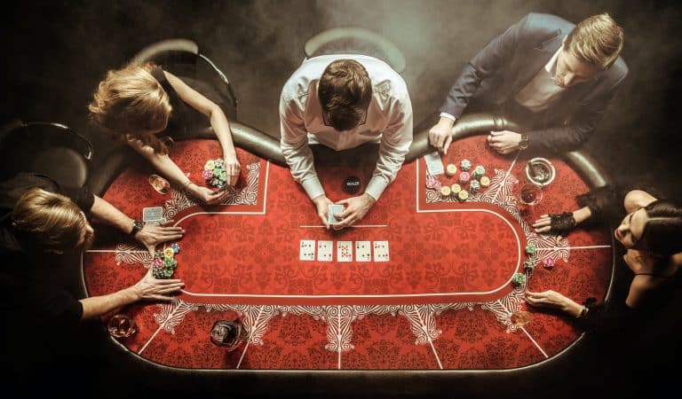 Vogelvlucht zicht van poker spelende mannen aan poker tafel - Verplichte Speellimieten 1 oktober 2024 - DutchGamblers