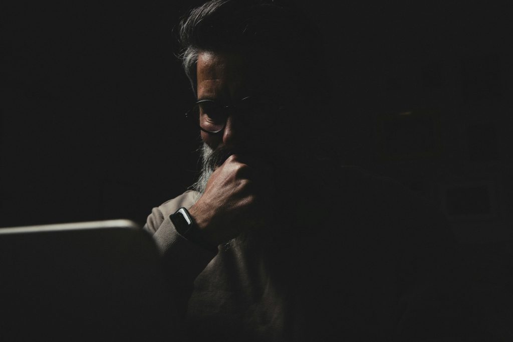 bearded man at a laptop at night. Internet addiction concept